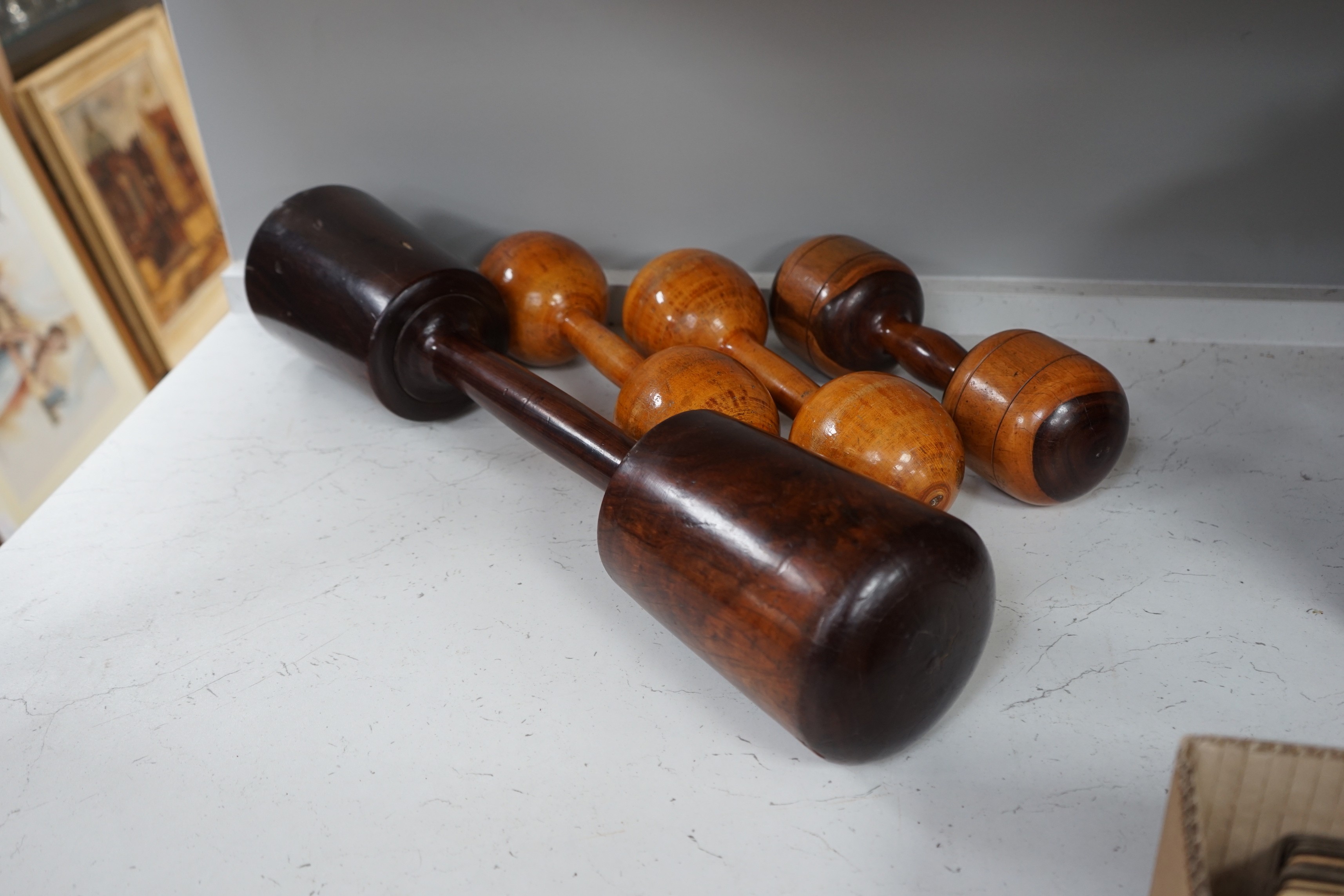 A large treen dumbbell / press together with three wooden American dumbbells by A.G. Spaulding & Bros